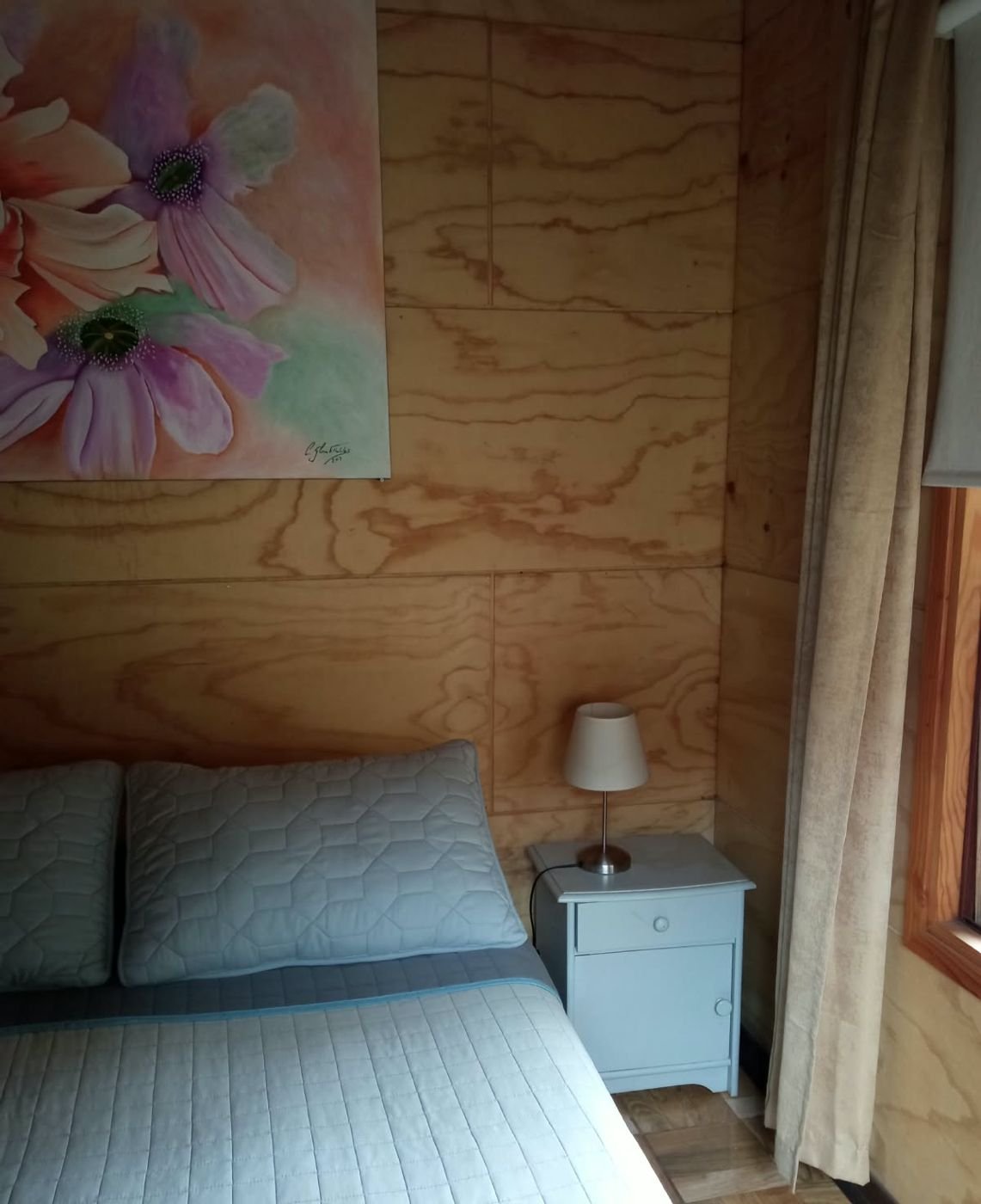 Cama con velador y cuadro de flores
