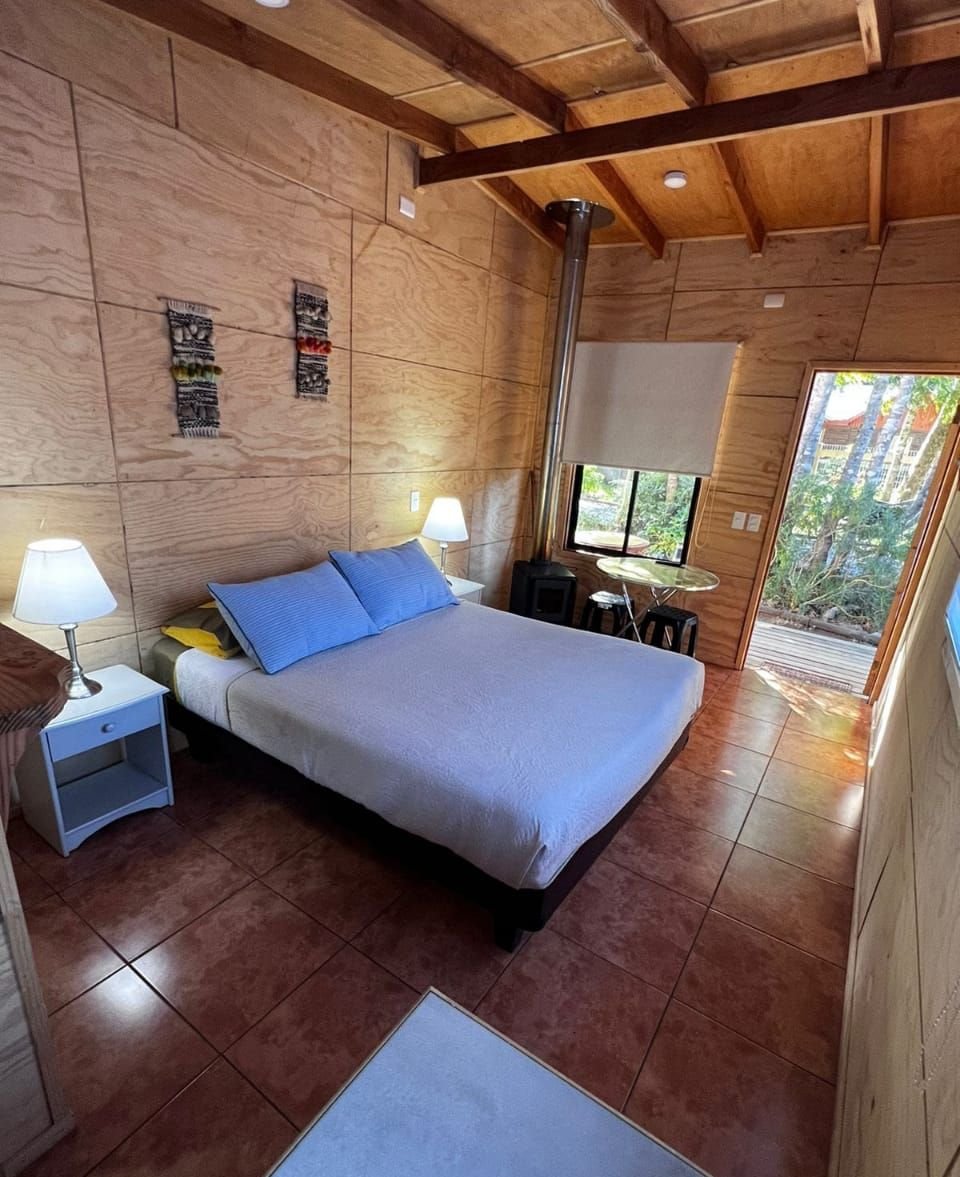 Dormitorio con estufa y ventanal, cabaña para 2 personas