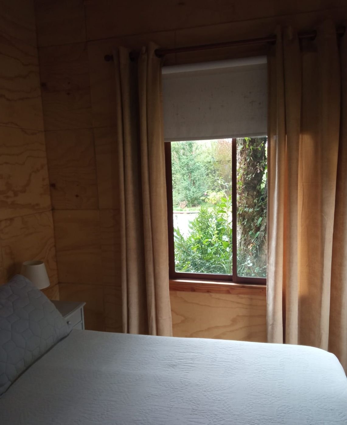 Dormitorio con cortinas y ventana al jardín